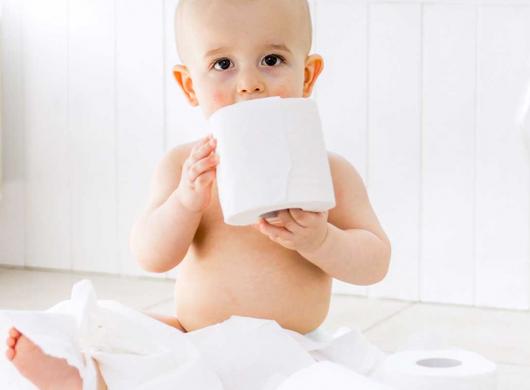 photo of a baby playing with toilet paper in the bathroom