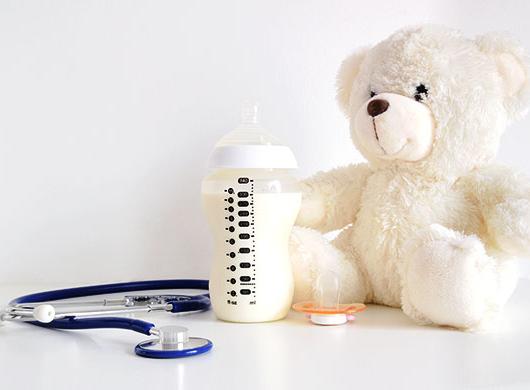 photo of a baby bottle, a teddy bear, a pacifier and a stethoscope