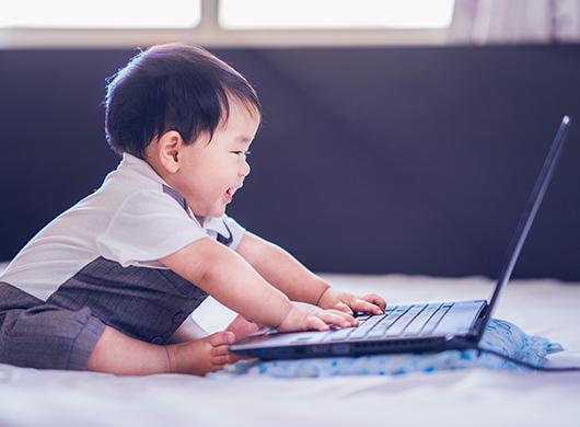 photo of a baby boy playing with a computer's keypad